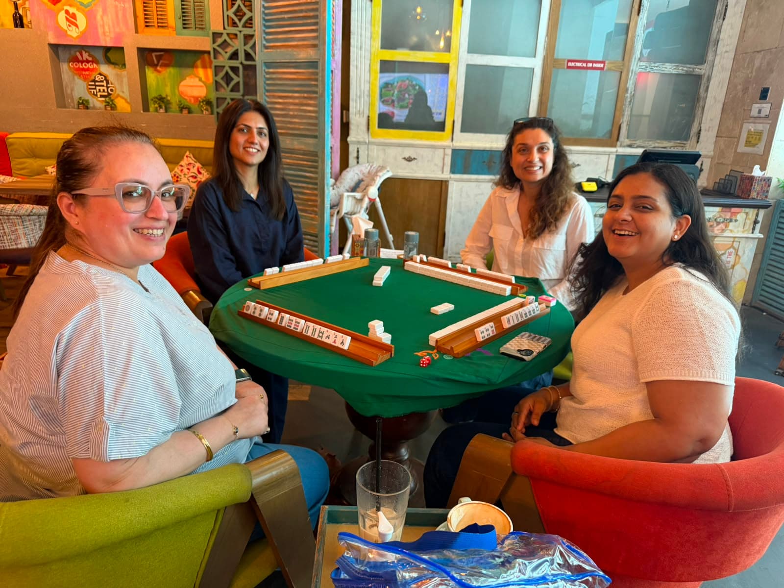 Four Mahjong players smiling around a beginner practice table in Dubai