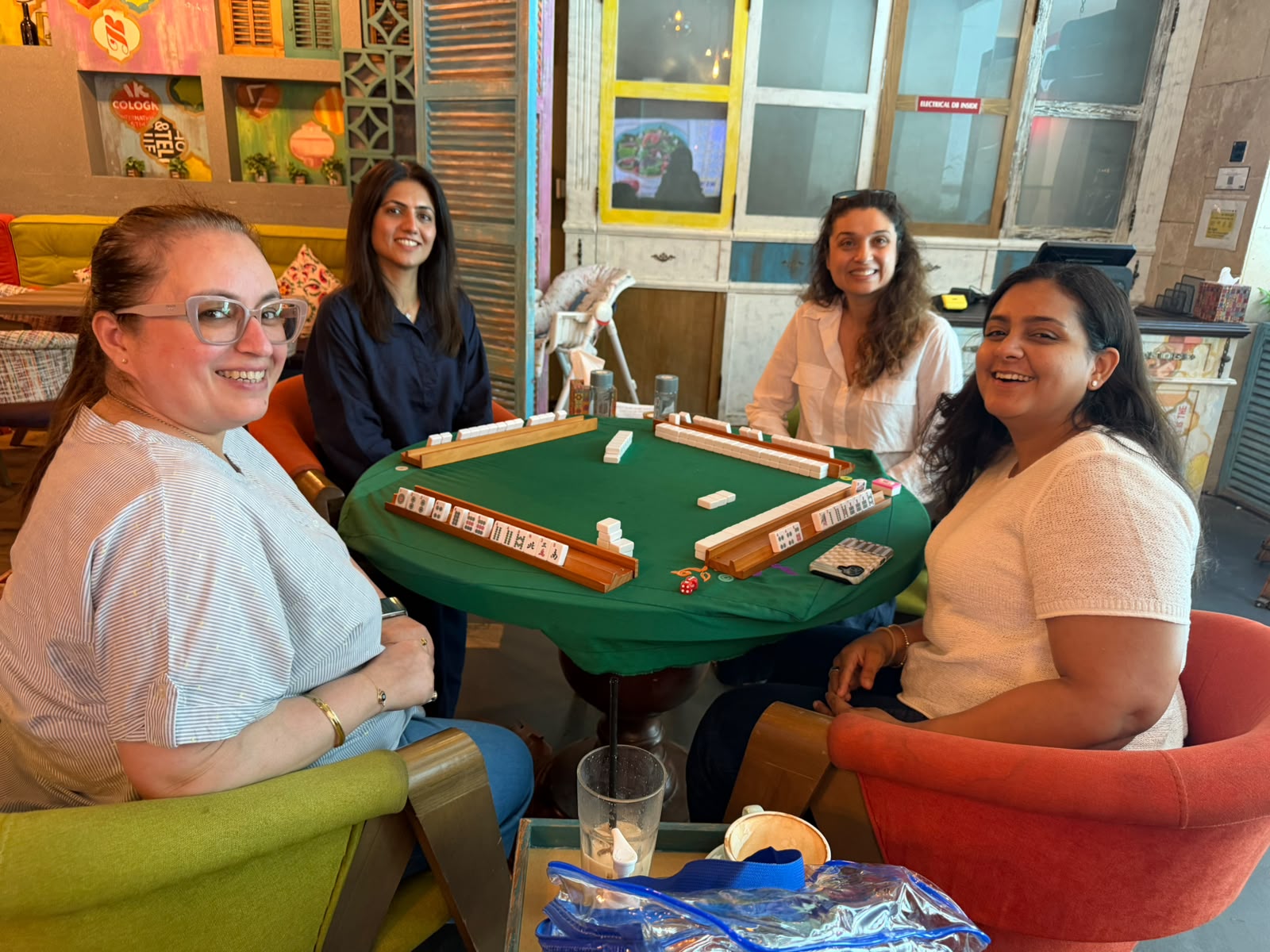 Four Mahjong players smiling around a beginner practice table in Dubai