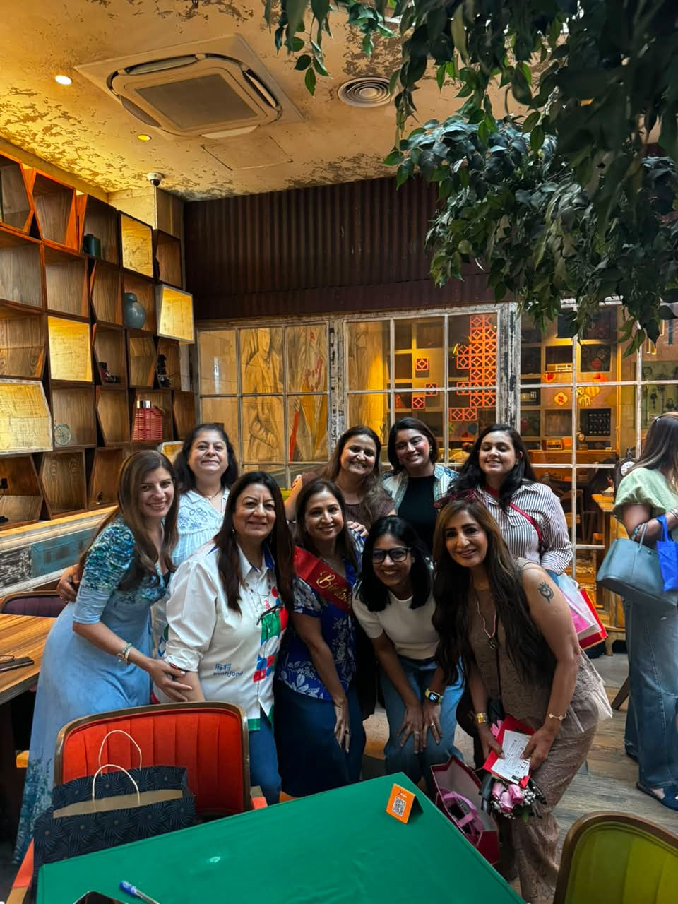 Mahjong players gathered for a group photo at a Dubai cafe table