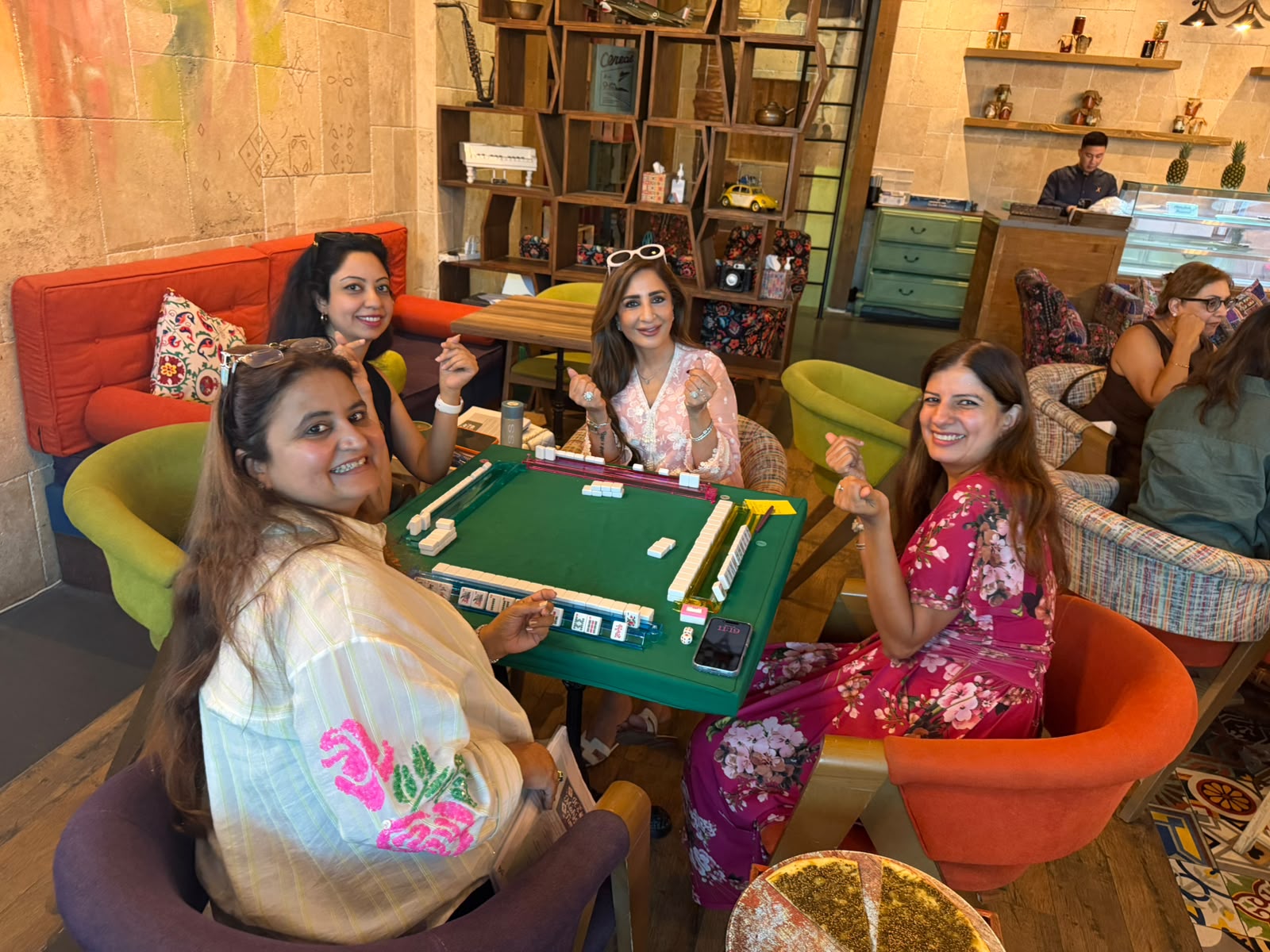 Four players smiling around a Mahjong open play table in Dubai